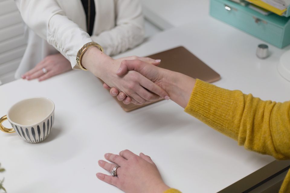 Two professionals shaking hands across a table after reaching an agreement